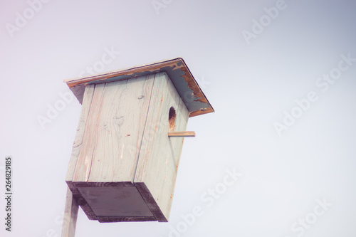 Blue wooden homemade birdhouse on the sky background