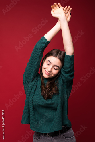 Joyful brunette pretty woman in sweater, looking at the camera over red background © F8  \ Suport Ukraine