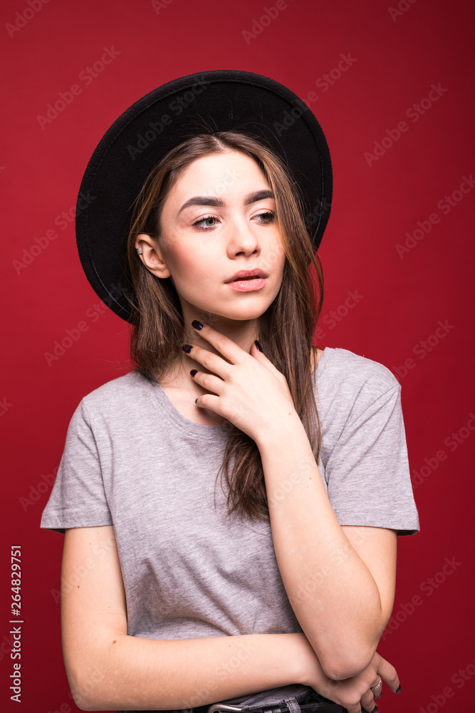 Portrait stylish girl wearing black hat isolated over red background Portrait stylish girl wearing black hat isolated over red background