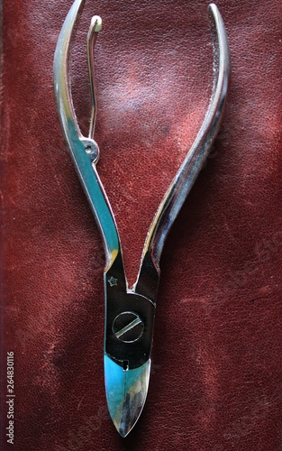 Close up of tongs on a background of red leather