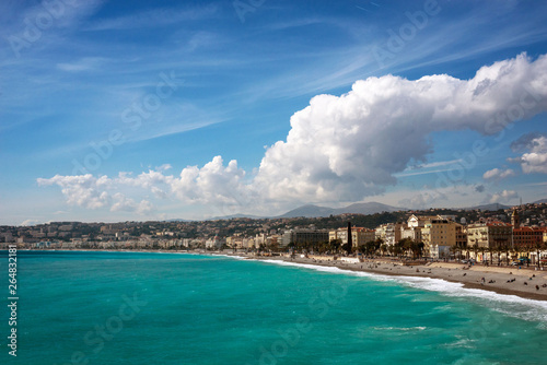 Nice  France  March 2019. Panorama. Azure sea  waves  English promenade and people resting. Rest and relaxation by the sea. On a sunny warm day  blue waves roll.