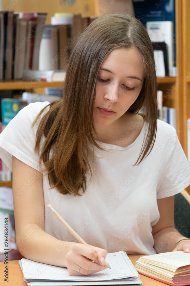 Student doing her homework in the school library Student doing her homework in the school library