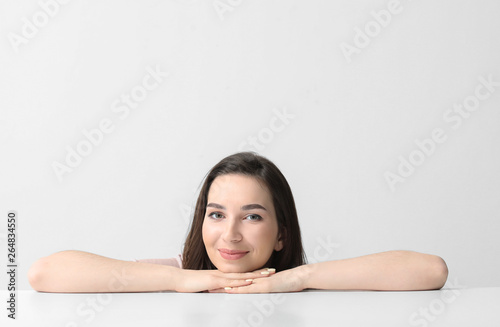 Beautiful young woman near table on white background
