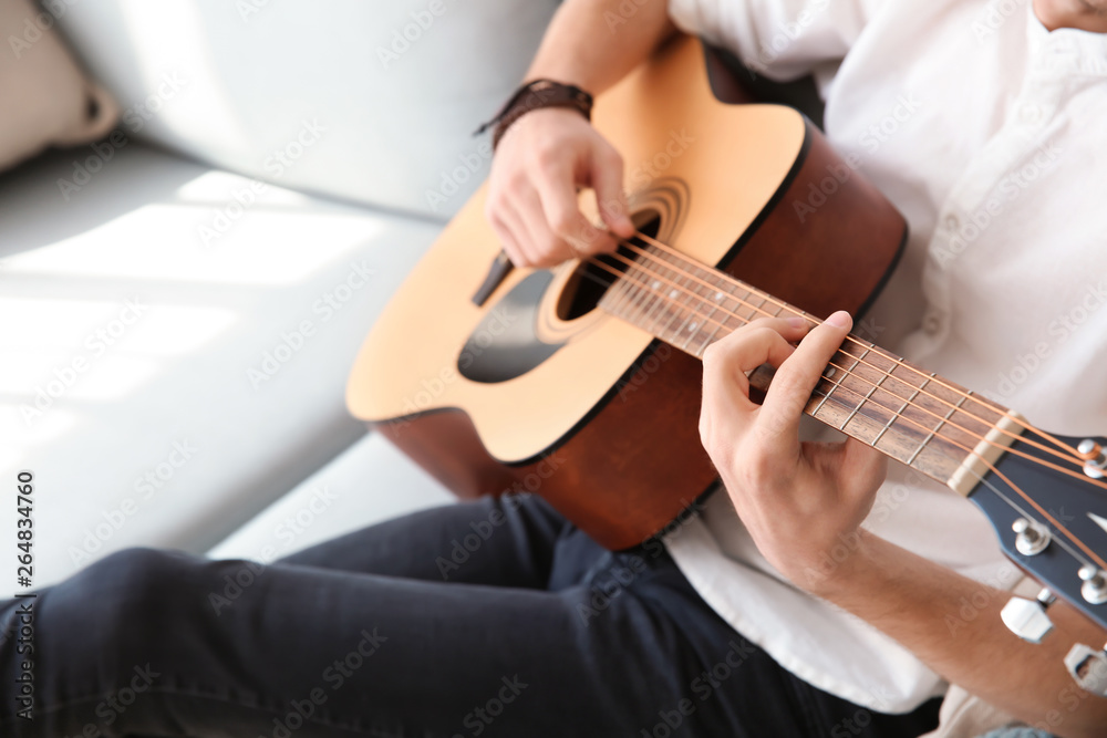 Handsome young man playing guitar at home