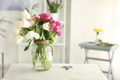 Vase with bouquet of flowers on table