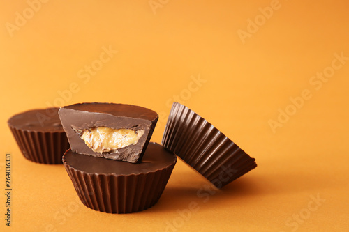 Tasty chocolate peanut butter cups on color background photo