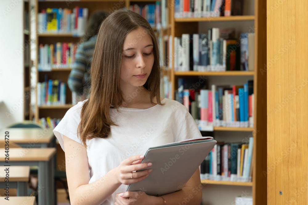 Portrait of a concentrated girl standing reading in the school library Portrait of a concentrated girl standing reading in the school library