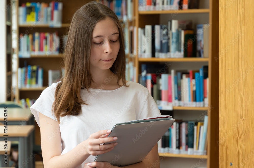 Portrait of a concentrated girl standing reading in the school library Portrait of a concentrated girl standing reading in the school library