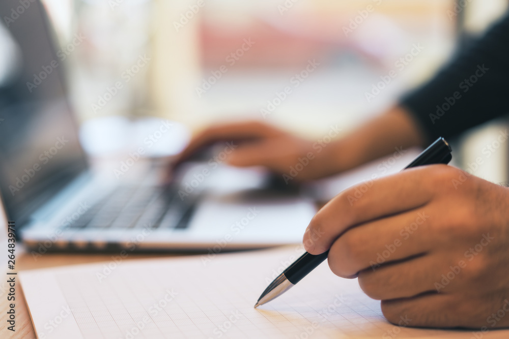 Sideview of guy doing paperwork with laptop Sideview of guy doing paperwork with laptop