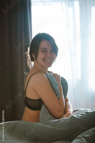 young pretty woman in black bra sitting on bed. morning time photo