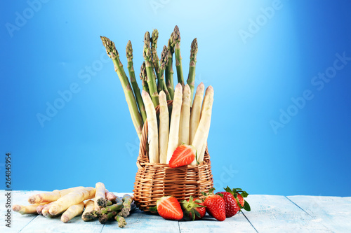 White and green asparagus with strawberries on wood