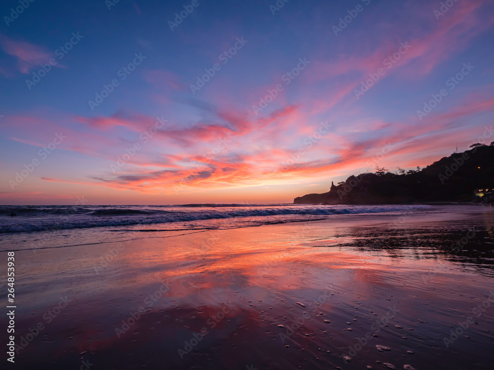 Beautiful reflection of the purple sunset sky on the beach of Montanita Ecuador