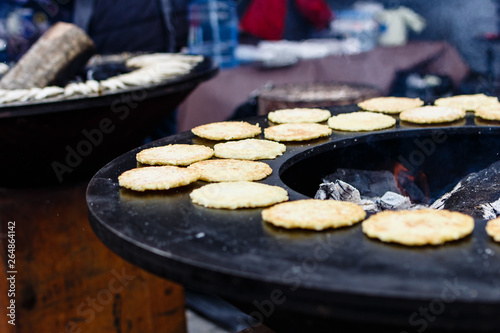 Delicious potato pancakes are frying on round flat grill on traditional spring food festival market in Vilnius, Lithuania