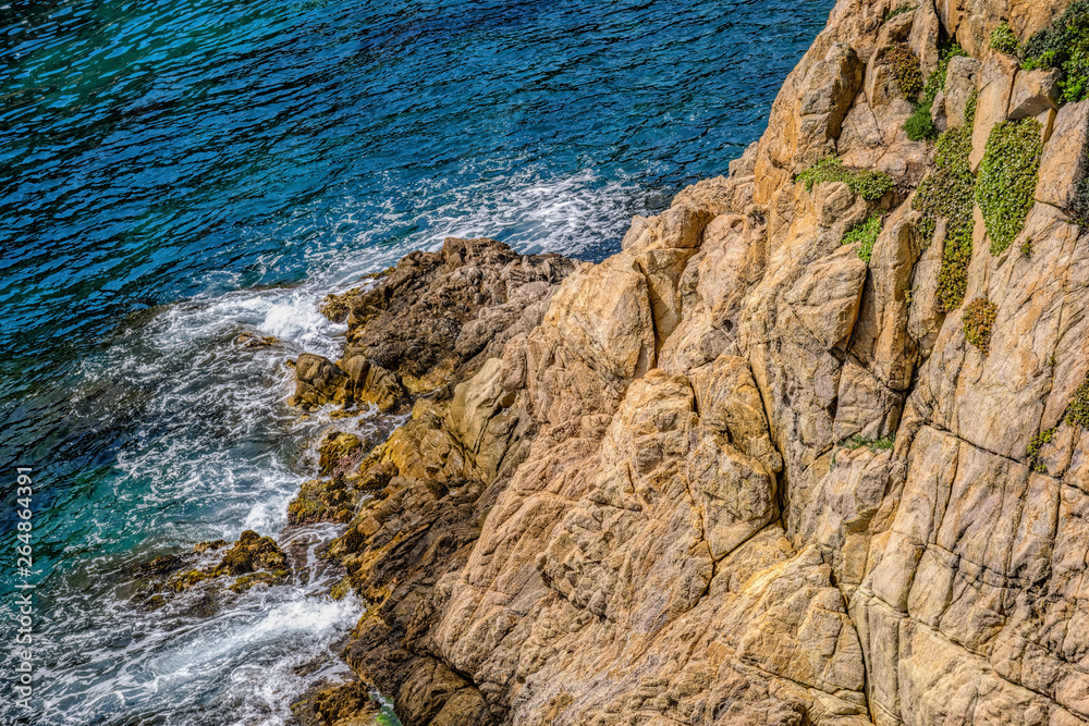 Beautiful view of clear mediterranean sea waves crash on rocks at wild stone beach in Europe. Blanes, Costa Brava, Spain. Beautiful view of clear mediterranean sea waves crash on rocks at wild stone beach in Europe. Blanes, Costa Brava, Spain.