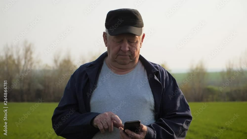 Mature farmer examining soil and using smartphone checking report of agriculture in a field. Mature farmer examining soil and using smartphone checking report of agriculture in a field.