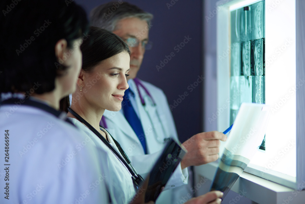 Group of doctors examining x-rays in a clinic, thinking of a diagnosis Group of doctors examining x-rays in a clinic, thinking of a diagnosis
