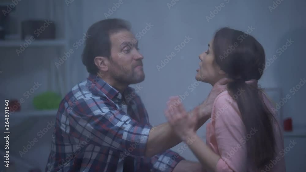 Mad man choking wife at home behind rainy window, assault in family, quarrel