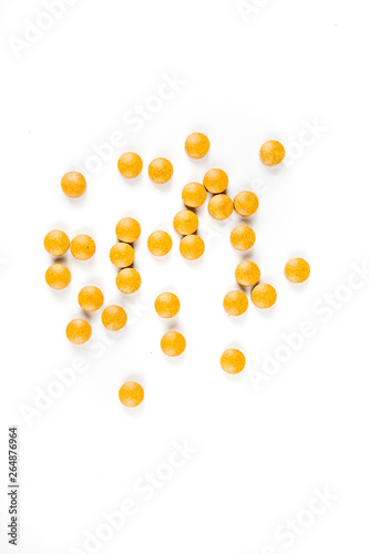 Scattered orange yellow pills over a white background