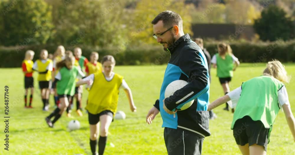 4K Portrait smiling sports coach, training with girls' soccer team on sports field. Slow motion.