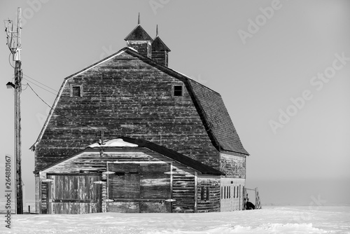 Black and white of an old, abandoned prairie barn surrounded by snow in Saskatchewan