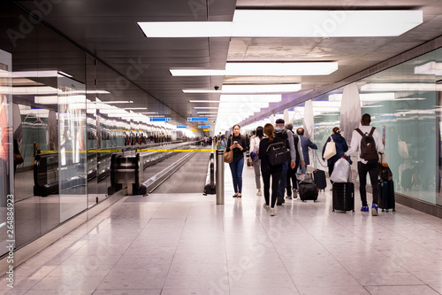 Woman standing in terminal airport with group of passenger walking.