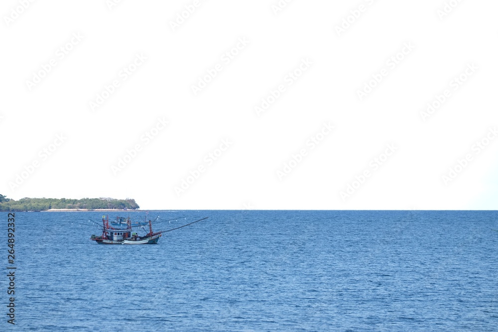 Blurred a fishing boat sailing in deep blue sea on white sky background 