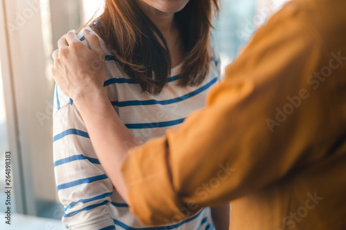 Psychologist sitting and touch young depressed asian woman for encouragement near window with low light environment, Selective focus, PTSD Mental health concept,