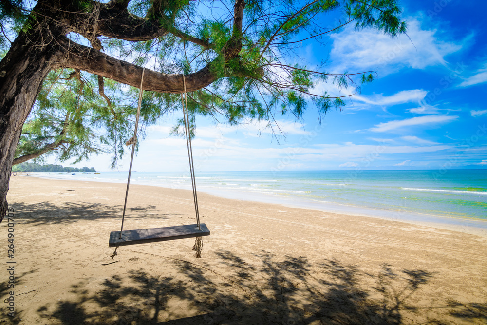 Wooden swing hanging from a tree on the beach. A tropical beach in southern part of Thailand in sunny day. Wooden swing hanging from a tree on the beach. A tropical beach in southern part of Thailand in sunny day.