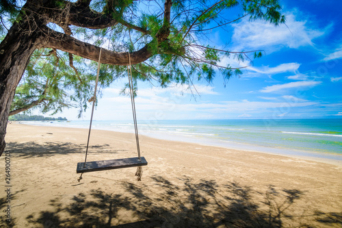 Wooden swing hanging from a tree on the beach. A tropical beach in southern part of Thailand in sunny day.