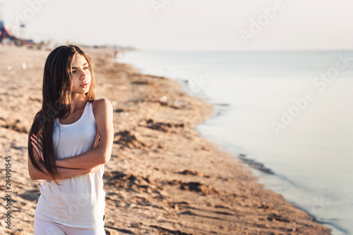 cute young girl resting on beach and looking into distance.