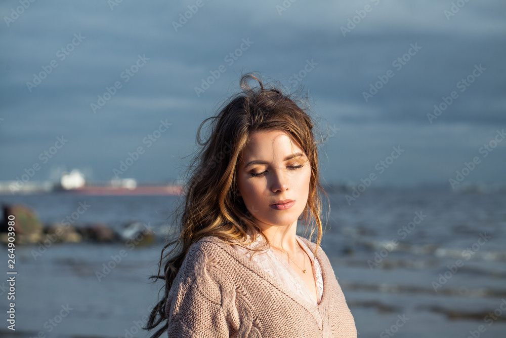 Pretty woman with long curly hair relaxing on ocean coast Pretty woman with long curly hair relaxing on ocean coast