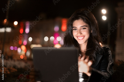 Happy girl making video-call on tablet in night city