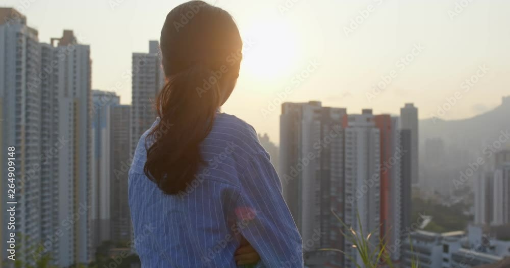 Confident woman look at the city with sunset time