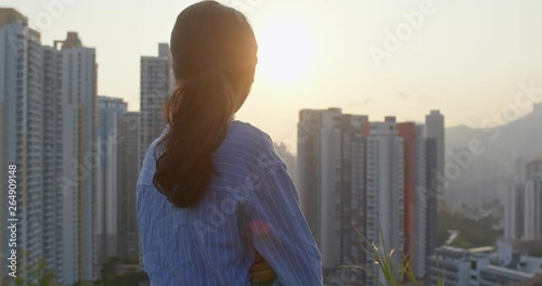 Confident woman look at the city with sunset time