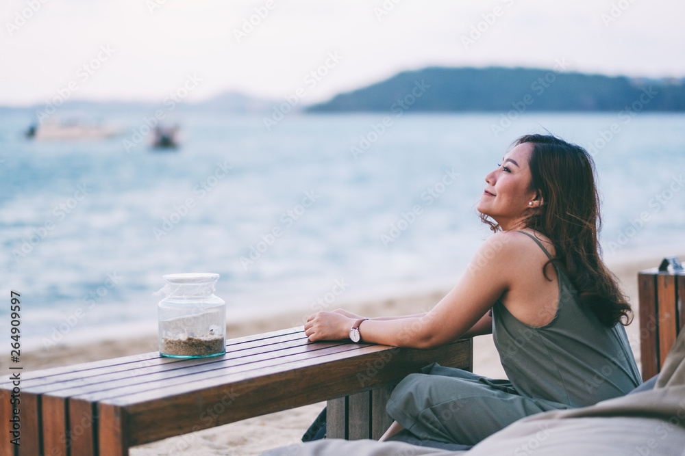 A beautiful asian woman enjoy sitting and relaxing on the beach by the seashore
