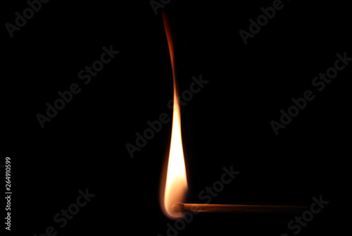 Burning match against black background in close up
