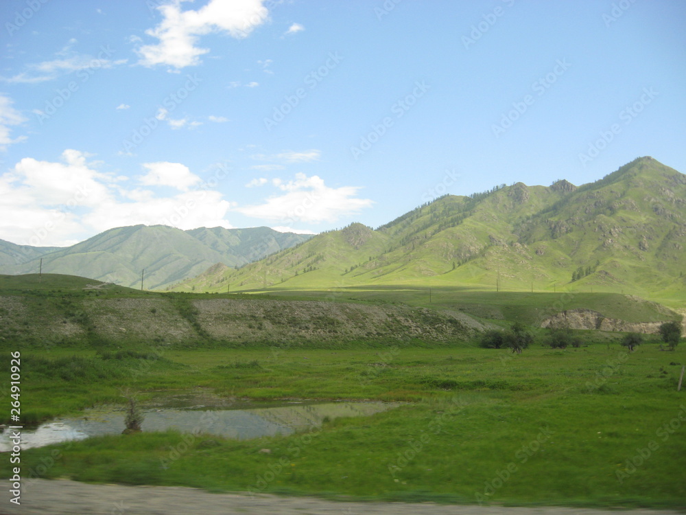 a small lake by the road in the Altai valley among the mountains on a Sunny day