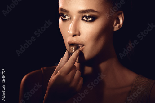 Εκτύπωση καμβά Beautiful girl eating chocolate on dark background