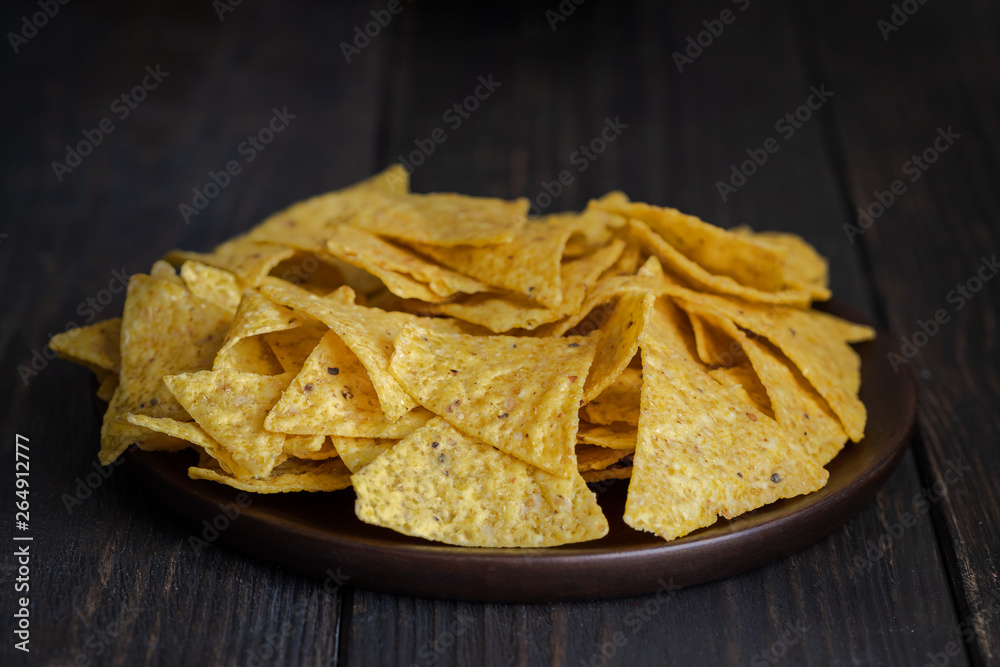 The most famous Mexican snack, nachos made con corn tortilla chips or totopos on wooden background. The most famous Mexican snack, nachos made con corn tortilla chips or totopos on wooden background.