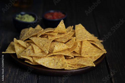 The most famous Mexican snack, nachos made con corn tortilla chips or totopos on wooden background.