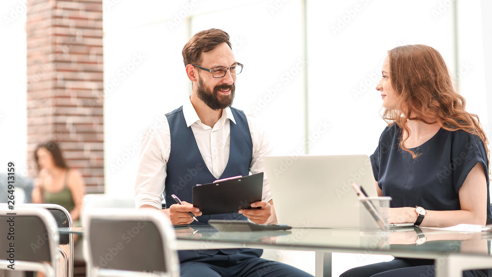 two employees discussing new ideas while sitting at the Desk two employees discussing new ideas while sitting at the Desk