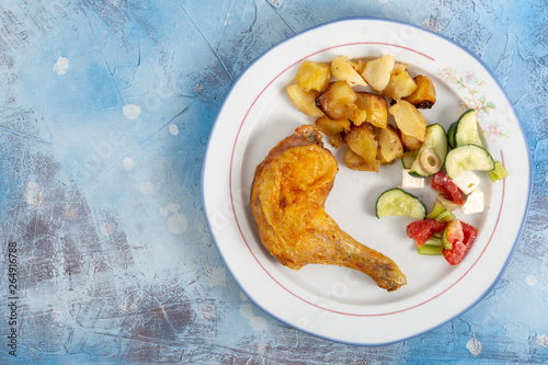 Fried Chicken Leg With Potatoes And Greece Salad On The Plate