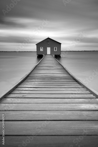 The Crawley Edge Boatshed. The blue boathouse on the Swan River with a wooden pier leading to the front door in Crawley, Perth, Western Australia.