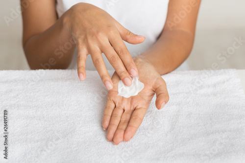 Skin nutrition. Girl spreading nourishing cream on palm