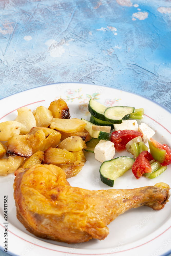 Fried Chicken Leg With Potatoes And Greece Salad On The Plate