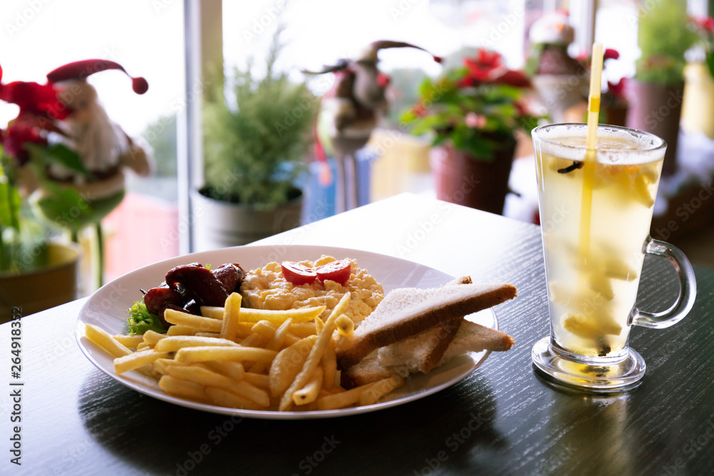 Breakfast with scrambled eggs, potatoes and tomatoes, served with ginger tea in a restaurant Breakfast with scrambled eggs, potatoes and tomatoes, served with ginger tea in a restaurant