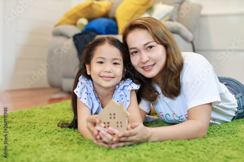 Asian family mom and daughter holding house model, meaning of saving with smiling and happy face.