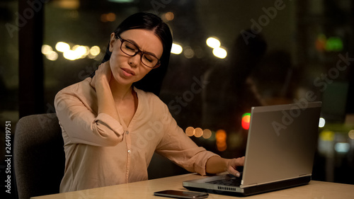 Woman suffering neck pain after working on laptop for long period, muscle strain