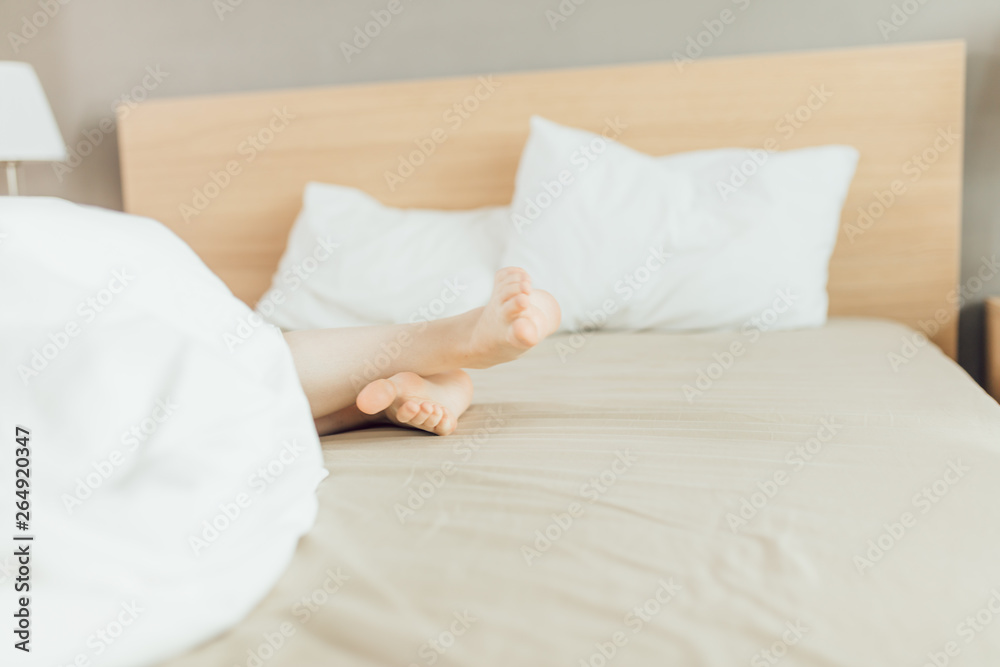woman's feet under the white blanket.rest time, holiday, weekend, woman spending time on the bed, laziness, legs care. close up cropped photo woman's feet under the white blanket.rest time, holiday, weekend, woman spending time on the bed, laziness, legs care. close up cropped photo