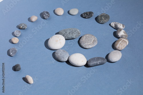 grey and white stones spiral on the blue background. close up photo